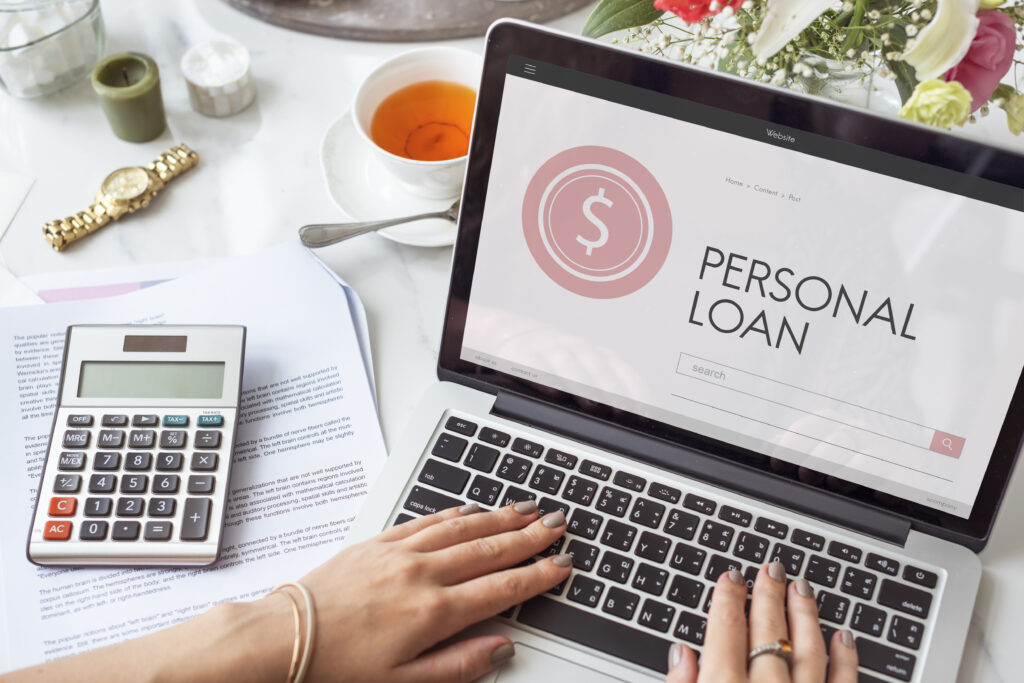 Debt consolidation using a personal loan – woman researching loan options on laptop with calculator and financial documents