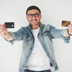 Young handsome male business executive in casual attire holding a credit card in the pockets on a white background. The concept of trading on the Internet and the ease of electronic money.